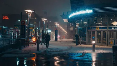 Snowy night in downtown Minneapolis with neon lights and people walking.