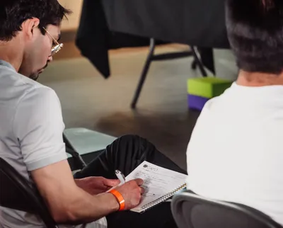 A man attentively taking notes during an indoor seminar, focused on learning.