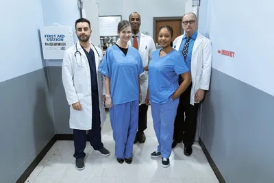 Group of diverse healthcare professionals smiling in a hospital hallway.