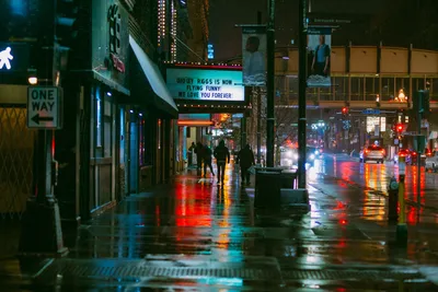 Rainy night scene in downtown Minneapolis with colorful reflections and city life vibes.