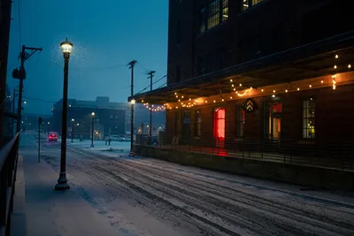 Charming winter evening on a snowy Minneapolis street with bright streetlights and string lights.