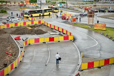 Overview of a city road construction site with pedestrian, buses, and safety barriers.
